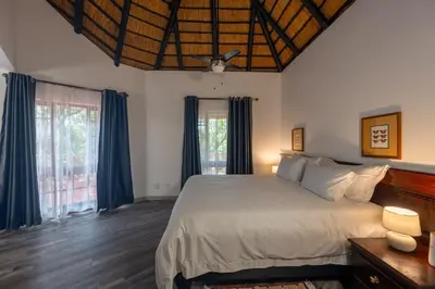 a bedroom with a large bed with blue curtains at Kruger Park Lodge Unit No 219 in Hazyview