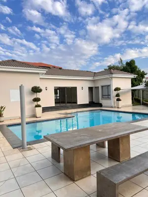 a swimming pool with a bench in front of a house at Midrand Urban Escape in Midrand