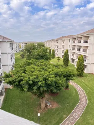 an apartment complex with a large tree in the yard at Midrand Urban Escape in Midrand