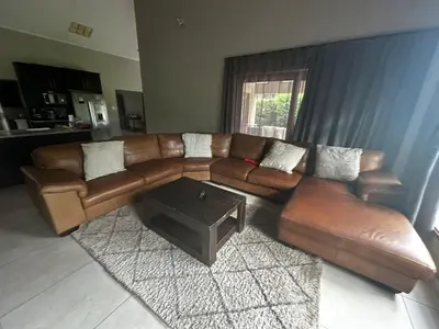 a living room with a brown leather couch and a table at Kumusha in Hartbeespoort
