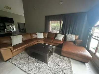 a living room with a brown couch and a coffee table at Kumusha in Hartbeespoort
