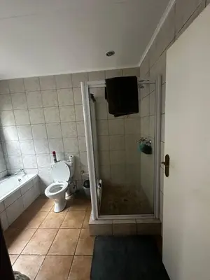 a bathroom with a shower and a toilet and a tub at Kumusha in Hartbeespoort