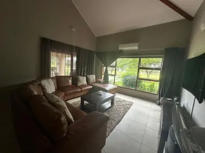 a living room with a couch and a large window at Kumusha in Hartbeespoort