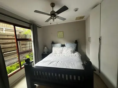 a bedroom with a bed with a ceiling fan at Kumusha in Hartbeespoort