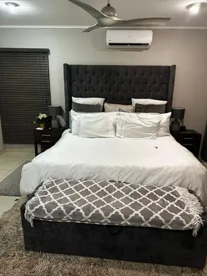 a bedroom with a large bed with a black headboard at Kumusha in Hartbeespoort