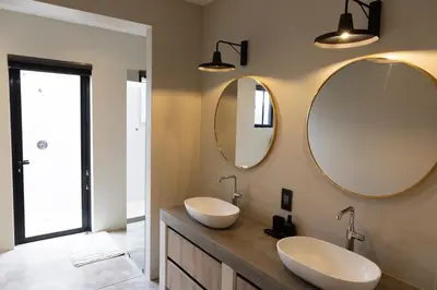 two sinks in a bathroom with two mirrors at Villa Kolobe in Hoedspruit