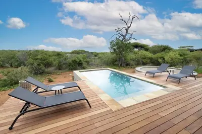 a deck with a swimming pool and two lounge chairs at Villa Kolobe in Hoedspruit