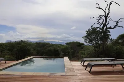 a swimming pool with two benches on a wooden deck at Villa Kolobe in Hoedspruit