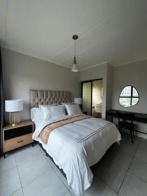 a bedroom with a large bed and a desk at Elegant Lifestyle Apartment in Waterfall in Midrand
