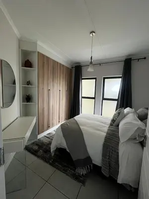 a bedroom with a large white bed and a desk at Elegant Lifestyle Apartment in Waterfall in Midrand