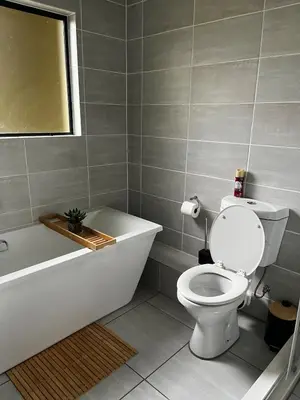 a bathroom with a tub and a toilet and a bath tub at Elegant Lifestyle Apartment in Waterfall in Midrand