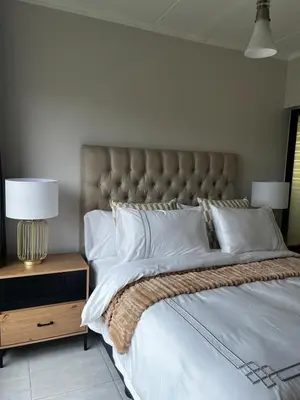 a bedroom with a large bed with white sheets and pillows at Elegant Lifestyle Apartment in Waterfall in Midrand