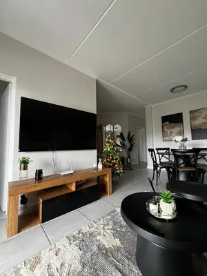 a living room with a television and a christmas tree at Elegant Lifestyle Apartment in Waterfall in Midrand