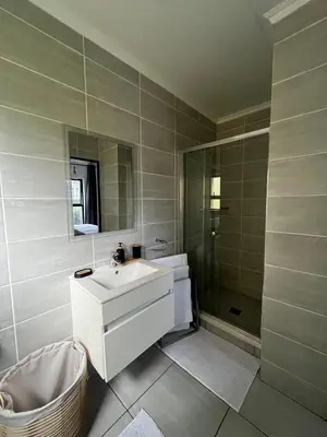 a white bathroom with a sink and a shower at Elegant Lifestyle Apartment in Waterfall in Midrand