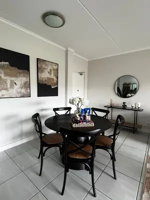 a dining room with a black table and chairs at Elegant Lifestyle Apartment in Waterfall in Midrand