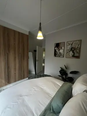 a bedroom with a white bed and a potted plant at Elegant Lifestyle Apartment in Waterfall in Midrand