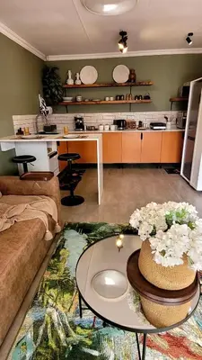a living room with a table and a kitchen at Iris HAVEN feel at home in Pretoria