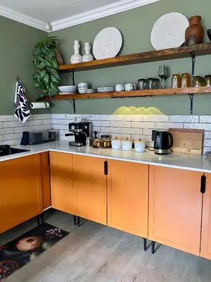 a kitchen with orange cabinets and plates on the shelves at Iris HAVEN feel at home in Pretoria