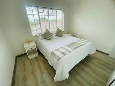 a white bedroom with a large bed and a window at Country Villa in Nelspruit