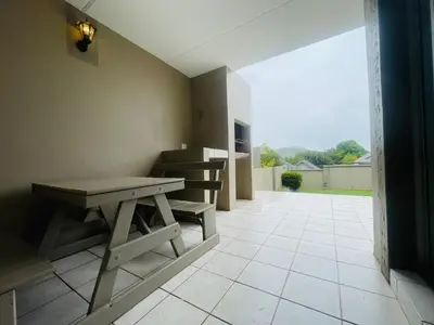 a room with a bench and a table on a tile floor at Country Villa in Nelspruit