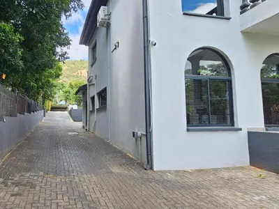 a white building with a brick sidewalk next to a street at Namloom Guesthouse in Pretoria