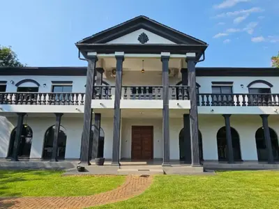 a large white house with a porch and a balcony at Namloom Guesthouse in Pretoria