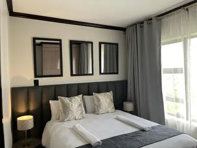 a bedroom with a large bed with two mirrors at Cozy retreat in Bluehills in Midrand