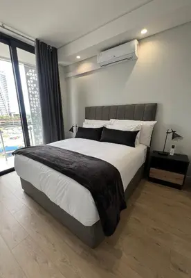 a bedroom with a large bed and a large window at Maboneng at Ellipse Waterfall in Midrand