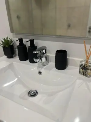 a bathroom sink with two black bottles on it at Maboneng at Ellipse Waterfall in Midrand