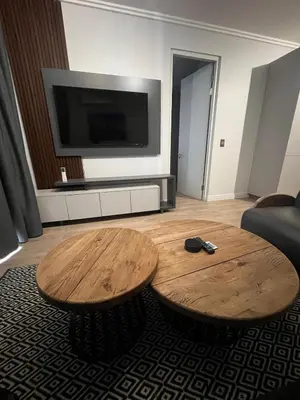 a living room with two wooden tables and a flat screen tv at Maboneng at Ellipse Waterfall in Midrand