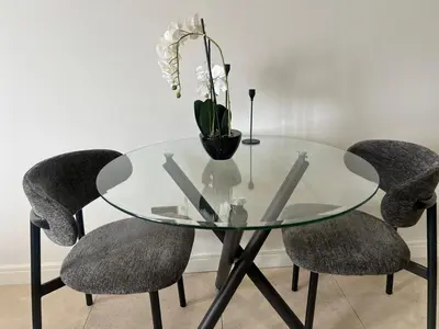 a glass table with two chairs and a vase with flowers at LeeMo at Ellipse Waterfall in Midrand