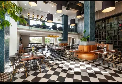 a restaurant with tables and chairs on a checkered floor at Luxurious queen room in Pretoria