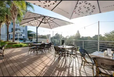 a patio with tables and chairs and an umbrella at Luxurious queen room in Pretoria