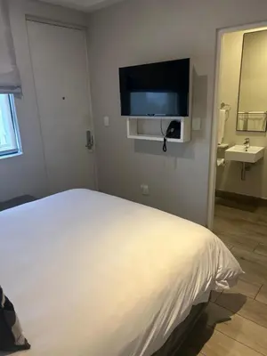 a bedroom with a white bed and a flat screen tv at Luxurious queen room in Pretoria