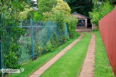 a garden with a fence and a red fence sidx sidx sidx at Kilmister Cottage in Dullstroom