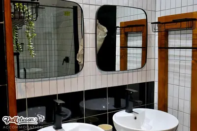 a bathroom with two sinks and two mirrors at Kilmister Cottage in Dullstroom
