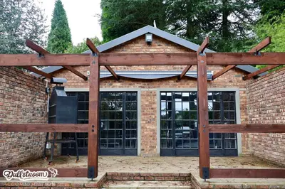 a large brick building with a wooden structure at Kilmister Cottage in Dullstroom