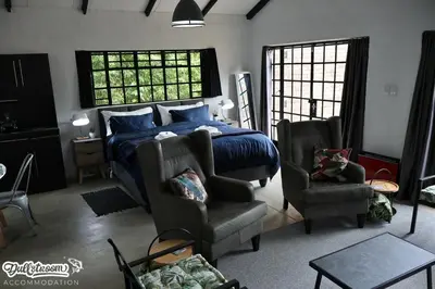 a bedroom with a bed and a couch and a chair at Kilmister Cottage in Dullstroom