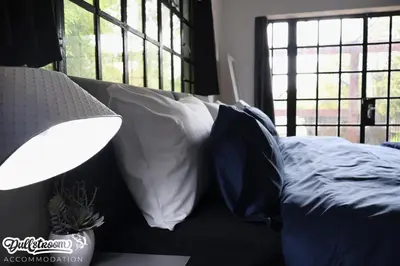 a bedroom with a bed with pillows and a lamp at Kilmister Cottage in Dullstroom