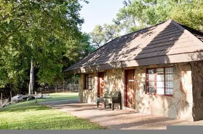 a stone building with a bench in a yard at Tumuga Game Ranches