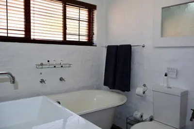 a white bathroom with a toilet and a sink at Delagoa Cottage Dullstroom in Dullstroom