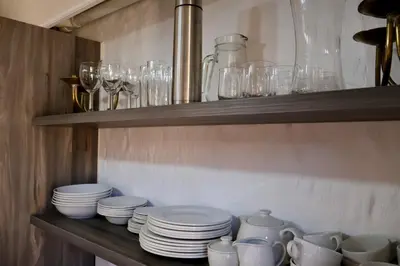 a shelf with plates and cups and glasses on it at Delagoa Cottage Dullstroom in Dullstroom