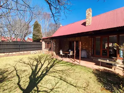 a brick house with a red roof and a yard at Delagoa Cottage Dullstroom in Dullstroom