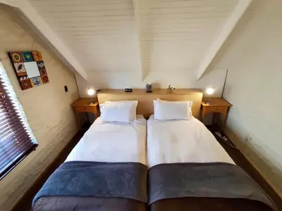 two beds in a small room with two windows at Delagoa Cottage Dullstroom in Dullstroom