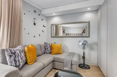 a living room with a couch and a mirror at Studio apartment, Ellipse Waterfall in Midrand