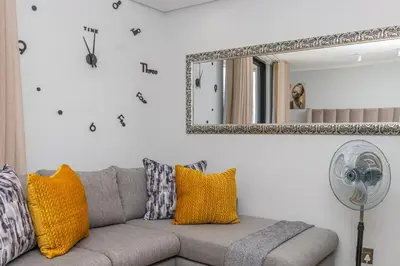 a living room with a couch and a mirror at Studio apartment, Ellipse Waterfall in Midrand
