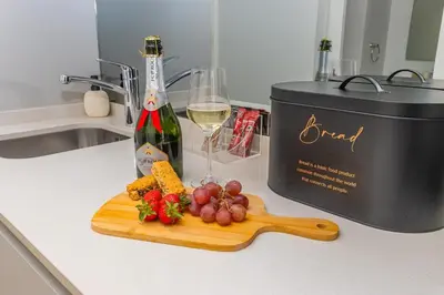 a bottle of wine and a cutting board with meat and vegetables at Studio apartment, Ellipse Waterfall in Midrand