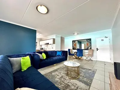a living room with a blue couch and a table at The Blyde - 3 Bedroom Lagoon Facing Luxury Apartment in Pretoria