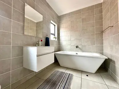 a bathroom with a tub and a sink and a mirror at The Blyde - 3 Bedroom Lagoon Facing Luxury Apartment in Pretoria