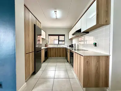 a kitchen with wooden cabinets and a tile floor at The Blyde - 3 Bedroom Lagoon Facing Luxury Apartment in Pretoria